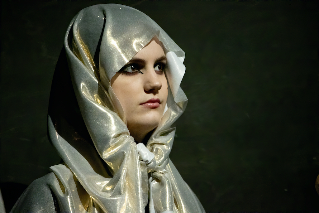 Close-up photo of an actress wearing a shiny hood.